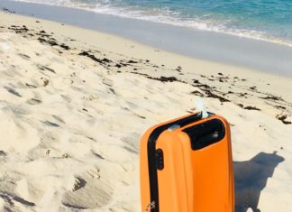 Orange suitcase on the sand