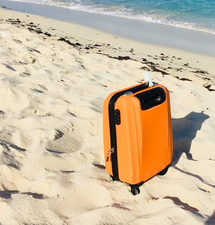Orange suitcase on the sand