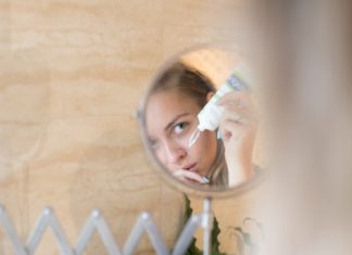 Woman putting on skincare in a mirror