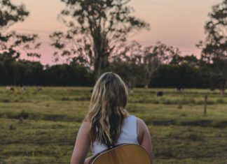 Girl with a guitar in field